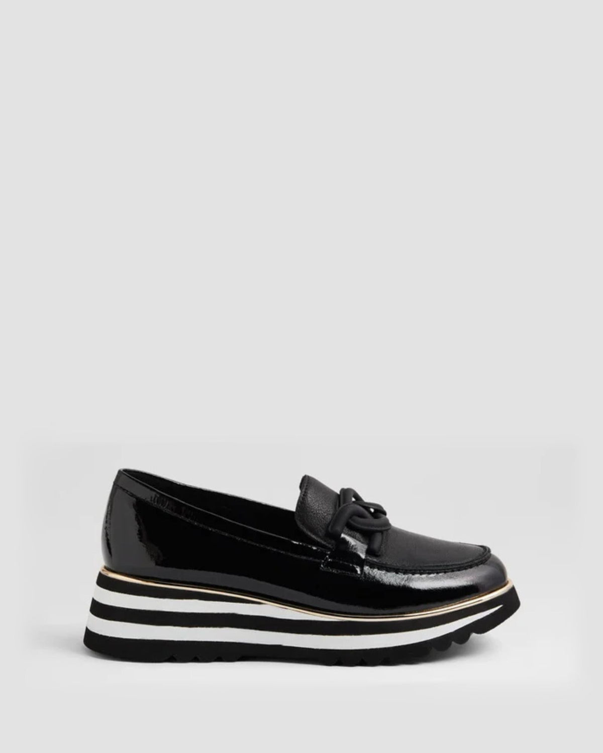 Black patent leather loafer with a white sole on a light gray background